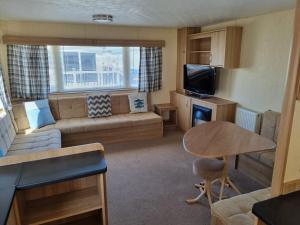 a small living room with a couch and a table at PG49 8 BERTH PET FRIENDLY CARAVAN GOLDEN PALM in Chapel Saint Leonards