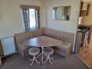 a small kitchen with a table and a couch at PG49 8 BERTH PET FRIENDLY CARAVAN GOLDEN PALM in Chapel Saint Leonards