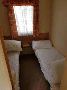 two beds in a small room with a window at PG49 8 BERTH PET FRIENDLY CARAVAN GOLDEN PALM in Chapel Saint Leonards