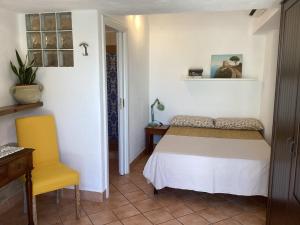 een slaapkamer met een bed en een gele stoel bij B&B Casetta Minghitto in Anacapri