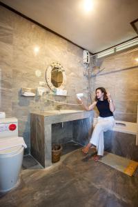 une femme assise sur un lavabo dans une salle de bains dans l'établissement Rajapruek Samui Resort - SHA Plus, à Lipa Noi