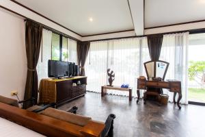 a living room with a couch and a tv and a piano at Rajapruek Samui Resort - SHA Plus in Lipa Noi