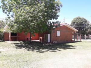 a small red brick building with a tree in the yard at Cabañas Don Pocho in Villa Cura Brochero