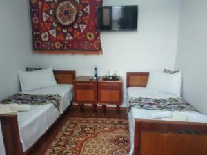 a small room with two beds and a rug at Al-Bashir in Bukhara