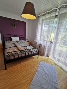 Un dormitorio con una cama y una pared morada. en Haus Buron, en Titisee-Neustadt