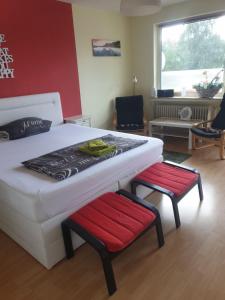 1 dormitorio con 1 cama blanca y 2 sillas rojas en Zentrales Apartement Bremen en Bremen