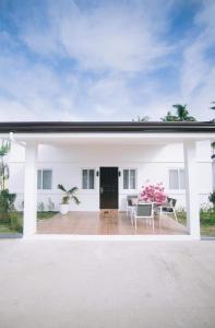a white house with a patio with a table and chairs at Kandaya Resort in Daanbantayan