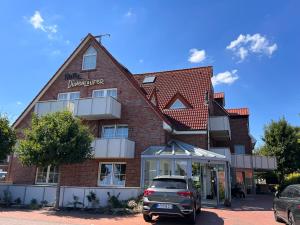 a building with a car parked in front of it at HOTEL DÜNENLÄUFER Carolinensiel in Carolinensiel