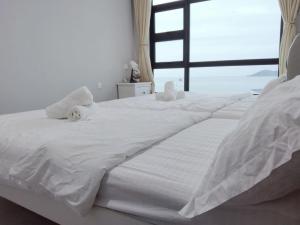 Cama blanca con sábanas blancas y ventana en JESSELTON QUAY SEA VIEW, en Kota Kinabalu