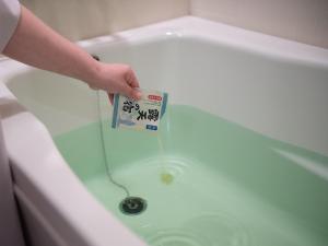 Hotel Vista Sapporo Nakajima Koen في سابورو: شخص يقف في حوض الاستحمام مع وضع علامة في الماء