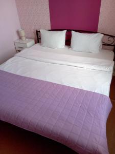 a large bed with a purple and white comforter at Hotel Kardinal in Vinnytsya