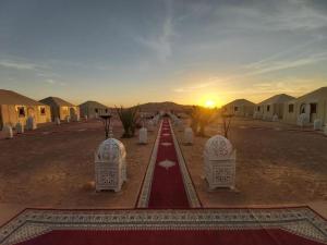 a road in the middle of a desert with a sunset at Sultan Luxury Camp in Merzouga