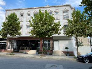 een wit gebouw met bomen ervoor bij Hotel Golden in Elbasan