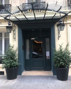 une porte d'entrée d'un bâtiment avec deux plantes en pot dans l'établissement Hotel de Montesquieu, à Paris