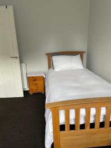 1 dormitorio con cama de madera y mesita de noche en Newsagents Flat en Lairg