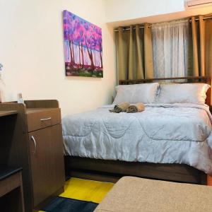 マニラにあるAmazing Condo @ the heart of Manilaのベッドルーム1室(ドレッサー付きのベッド1台、絵画付)
