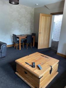 Habitación con mesa de madera, mesa y sillas. en Newsagents Flat en Lairg