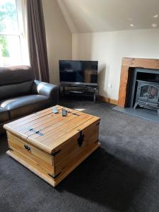 a living room with a coffee table in front of a fireplace at Newsagents Flat in Lairg