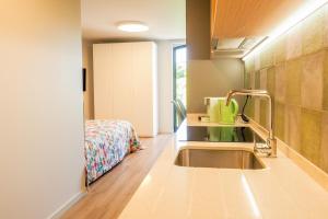 una cocina con fregadero y una cama en una habitación en RIACENTRUM - Smart Residence, en Aveiro