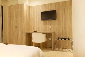 um quarto com uma cama e uma televisão na parede em Hotel El Djenina em Tânger