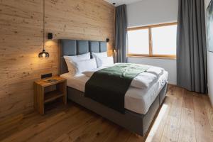 a bedroom with a large bed with a wooden wall at Puitalm - Natur I Apart I Hotel in Arzl im Pitztal