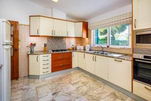 a kitchen with white cabinets and a tile floor at Casa Cupula in Poço Partido