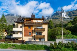 a building with balconies and a flag in front of a mountain at Pra d'Sura 115 in Maloja