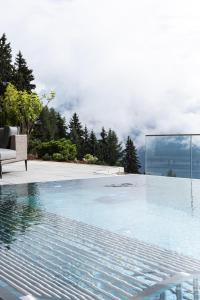 a swimming pool with a chair sitting next to at Puitalm - Natur I Apart I Hotel in Arzl im Pitztal