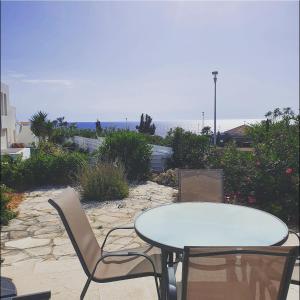 a table and chairs on a patio with the ocean at The SunSet 005 in Chlorakas