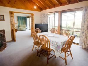 a dining room with a table and chairs and a television at Derwent Vista in Austins Ferry