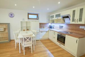 cocina con armarios blancos, mesa y sillas en Apartmán Casia, en Jeseník
