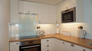 a kitchen with white cabinets and a counter top at Wheat Cottage - 5* Cyfie Farm with private covered hot tub in Llanfyllin