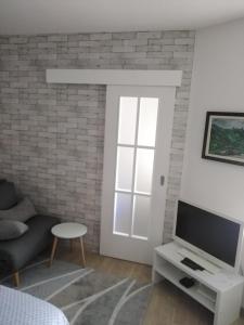 een woonkamer met een tv en een bakstenen muur bij Apartman Regina in Užice