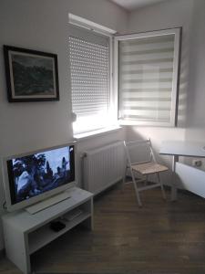 a living room with a tv and a table and a window at Apartman Regina in Užice