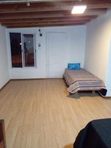 Habitación con cama y suelo de madera. en Departamentos Sarmiento 3, en San Luis