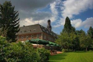 ein großes Backsteingebäude mit einem Uhrturm oben in der Unterkunft Nikolauskloster in Jüchen