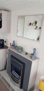 a living room with a fireplace and a mirror at The selsey retreat in Selsey