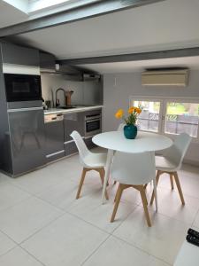 a kitchen with a white table and chairs in a kitchen at Villa L'Abaguie-Charmant logement au calme entre mer et montagne in Cagnes-sur-Mer
