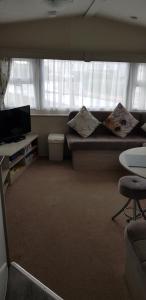 a room with a bed and a tv and a couch at The selsey retreat in Selsey