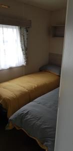 two beds in a small room with a window at The selsey retreat in Selsey +5 photos