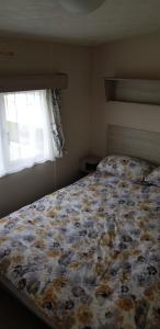 a bedroom with a bed with a floral comforter and a window at The selsey retreat in Selsey