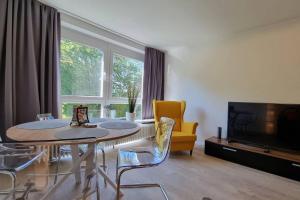 a living room with a table and a yellow chair at Strandappartement 2 Minuten vom Südstrand in Wilhelmshaven