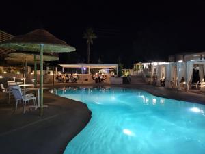 聖瑪格利特迪普拉的住宿－Oasi Blu Sardinia，游泳池在晚上配有桌椅