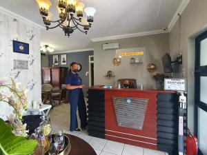 Ledumo Guest lodge في ويتبانك: رجل يقف عند كاونتر في مطعم