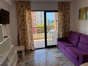 ein Wohnzimmer mit einem lila Sofa und einem Balkon in der Unterkunft Apartments Carlos V in Benidorm