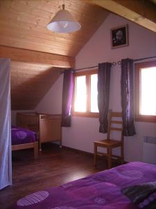 a bedroom with a bed and a chair and windows at Gite du Brin d'Herbe in Pontarlier