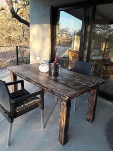 een houten tafel, een stoel, een tafel en een raam bij Palahala in Marloth Park