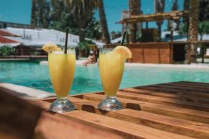 two glasses of orange juice sitting on a table near a swimming pool at Hotel Puesta del Sol in San Rafael