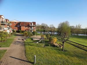 Blick auf einen Park mit Fluss und Gebäuden in der Unterkunft Auszeit am Fähranleger in Grünendeich