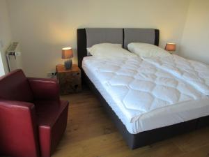 ein Schlafzimmer mit einem großen weißen Bett und einem Stuhl in der Unterkunft Auszeit am Fähranleger in Grünendeich